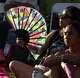 A guest used a large colorful fan to help beat the heat while listening to a stage performance at Asian American Heritage Festival, which featured dance performances, musical acts and a host of vendors. The event drew thousands to Downtown Square in Garland on May 16, 2026.