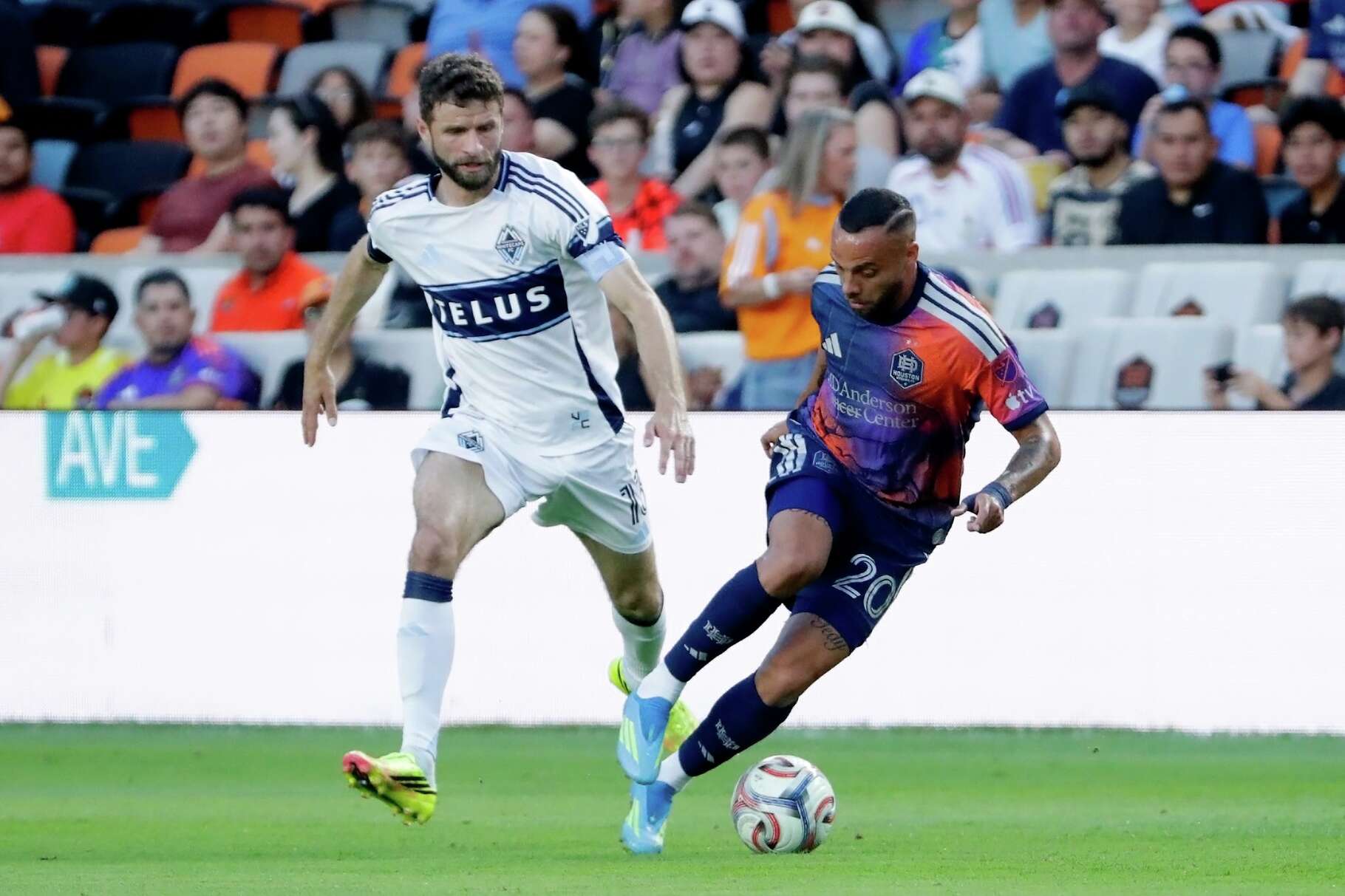 Houston Dynamo FC midfielder Guilherme Santos, right, moves the ball past Vancouver Whitecaps FC midfielder Thomas Muller during the first half of an MLS soccer match, Saturday, May 16, 2026, in Houston.
