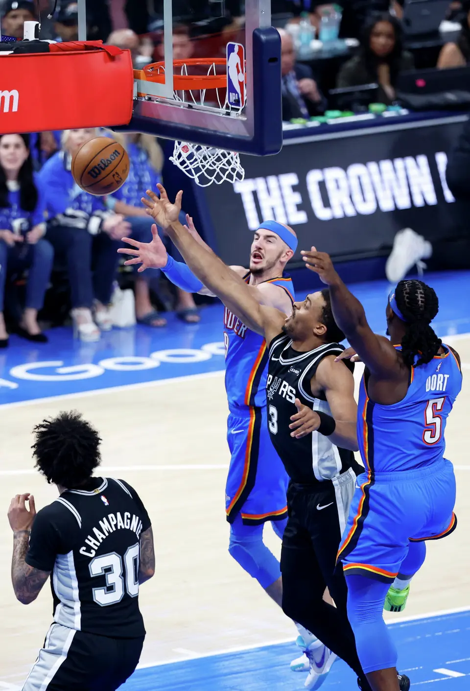 San Antonio Spurs forward Keldon Johnson (3) battles with Oklahoma City Thunder guard Alex Caruso (9) and Thunder guard Luguentz Dort (5) for a rebound during the first half of Game 1 of the Western Conference Finals at Paycom Center in Oklahoma City, Monday, May 18, 2026.