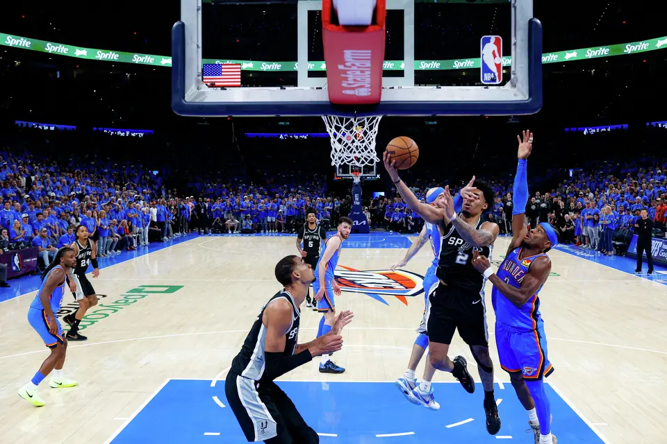 San Antonio Spurs guard Dylan Harper (2) lays the ball in as he is guarded by Oklahoma City Thunder guard Alex Caruso (9) and guard Shai Gilgeous-Alexander (2) during Game 1 of the Western Conference Finals at Paycom Center in Oklahoma City, Monday, May 18, 2026. The Spurs defeated the Thunder 122-115 in double overtime.