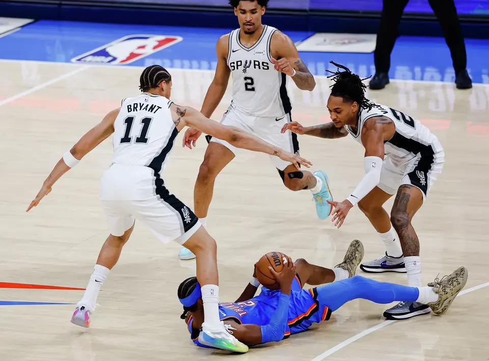 Oklahoma City Thunder guard Shai Gilgeous-Alexander (2) goes to the ground while guarded by San Antonio Spurs forward Carter Bryant (11), San Antonio Spurs guard Dylan Harper (2) and San Antonio Spurs guard Devin Vassell (24) during the first half of Game 2 of the Western Conference Finals at Paycom Center in Oklahoma City, Wednesday, May 20, 2026.