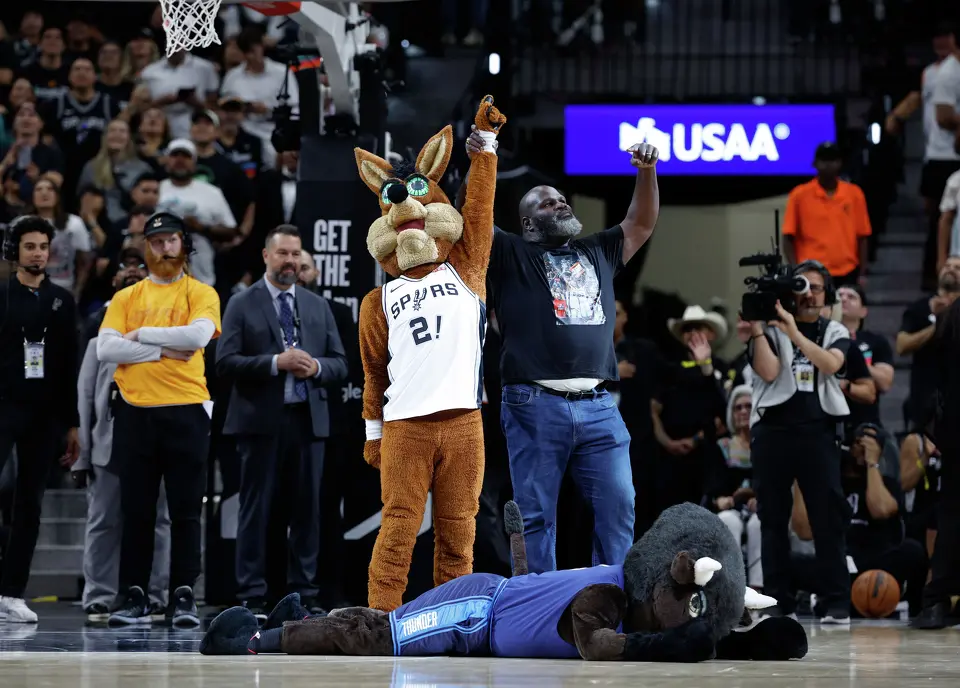 The Spurs Coyote and a fan celebrate as Oklahoma’s Rumble the Bison falls to the floor during the first quarter of Game 4 of the Western Conference Finals at Frost Bank Center in San Antonio, Sunday, May 24, 2026.