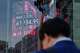 FILE - A person stands in front of an electronic stock board showing Japan's Nikkei index, seen through the glass wall of an office building in Tokyo, May 7, 2026.
