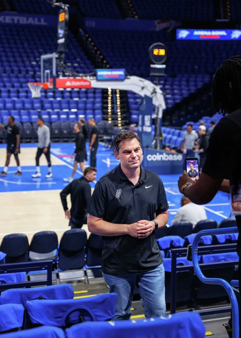 San Antonio Spurs content producer Rashad White, right, films a video of Spurs radio host Dan Weiss talking to fans during the team’s shootaround practice at the Paycom Center in Oklahoma City, Monday, May 18, 2026, as Spurs prepare to take on the Oklahoma City Thunder in Game 1 of the Western Conference Finals.