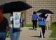 Ashley Monroe, left, and Ethea Farahkhan are shaded by umbrellas as they hand out candidate information at the Sunnyside Multi-Service Center during the primary runoff election in Houston Tuesday, May 26, 2026.