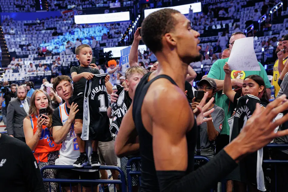 Zayden Salazar, 7, yells for San Antonio Spurs center Victor Wembanyama’s attention as Mateo Salazar lifts him up before Game 5 of the Western Conference Finals against the Oklahoma City Thunder at Paycom Center in Oklahoma City, Tuesday, May 26, 2026.