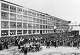 Ford history. It's factory in Highland park Michigan USA was a production facility for the Model T car and has become known for being the first factory in history to assemble cars on a moving assembly line. Picture shows the factory building and chassis in mass outside it. 1913