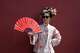 A woman holds up a fan with the words "May you be happy and prosperous" wearing historical Chinese costume outside the Forbidden City in Beijing on Saturday, April 4, 2026.