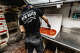 A worker cuts a pizza at Sally's Apizza in New Haven, Conn.