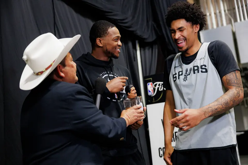 Comedian Guillermo Rodriguez, left, and San Antonio Spurs guard De'aaron Fox, center, interact with guard Dylan Harper after a news conference at Frost Bank Center in San Antonio, Tuesday, June 2, 2026, prior to the start of the NBA Finals basketball series against the New York Knicks. “I can’t drink,” said Harper, who is only 20 years old, after Rodriguez and Fox showed him a bottle of tequila.