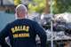 A flower rests on a fence as a Dallas Fire-Rescue firefighter looks over debris at the site of a deadly explosion and fire at The Clyde apartment building in Oak Cliff on Wednesday, June 3, 2026, in Dallas.