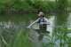 Drake University student Harrison Ziegler dips a bottle in a stream to collect a water sample Wednesday, May 6, 2026, in Des Moines, Iowa.