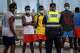 FILE - A police officer speaks with migrants and asylum-seekers in Gran Canaria island, Spain, Tuesday, Aug. 18, 2020.