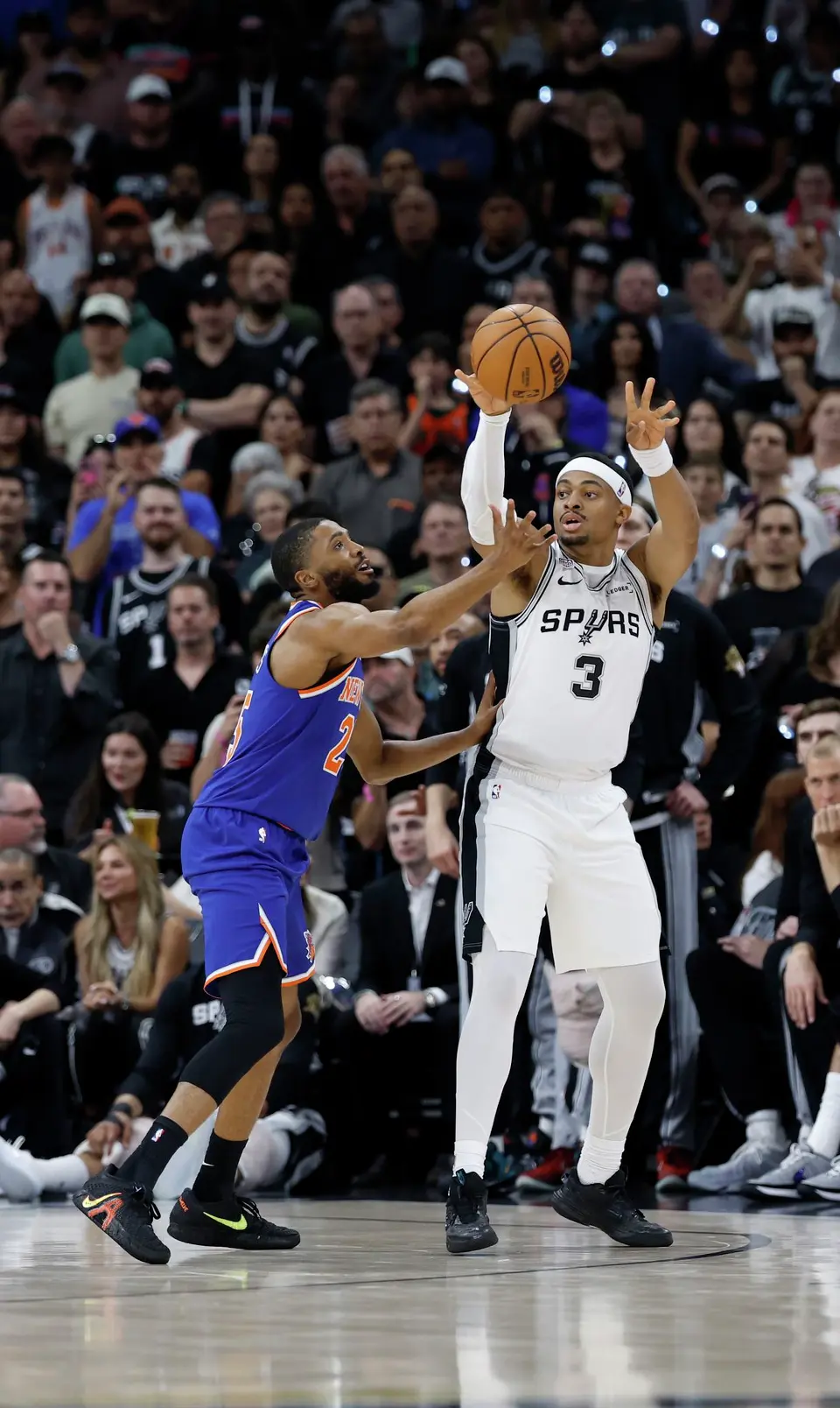 San Antonio Spurs forward Keldon Johnson (3) passes off the ball while being defended by New York Knicks guard Mikal Bridges (25) during the first quarter of Game 2 of the NBA Championship at Frost Bank Center in San Antonio on Friday, June 5, 2026.