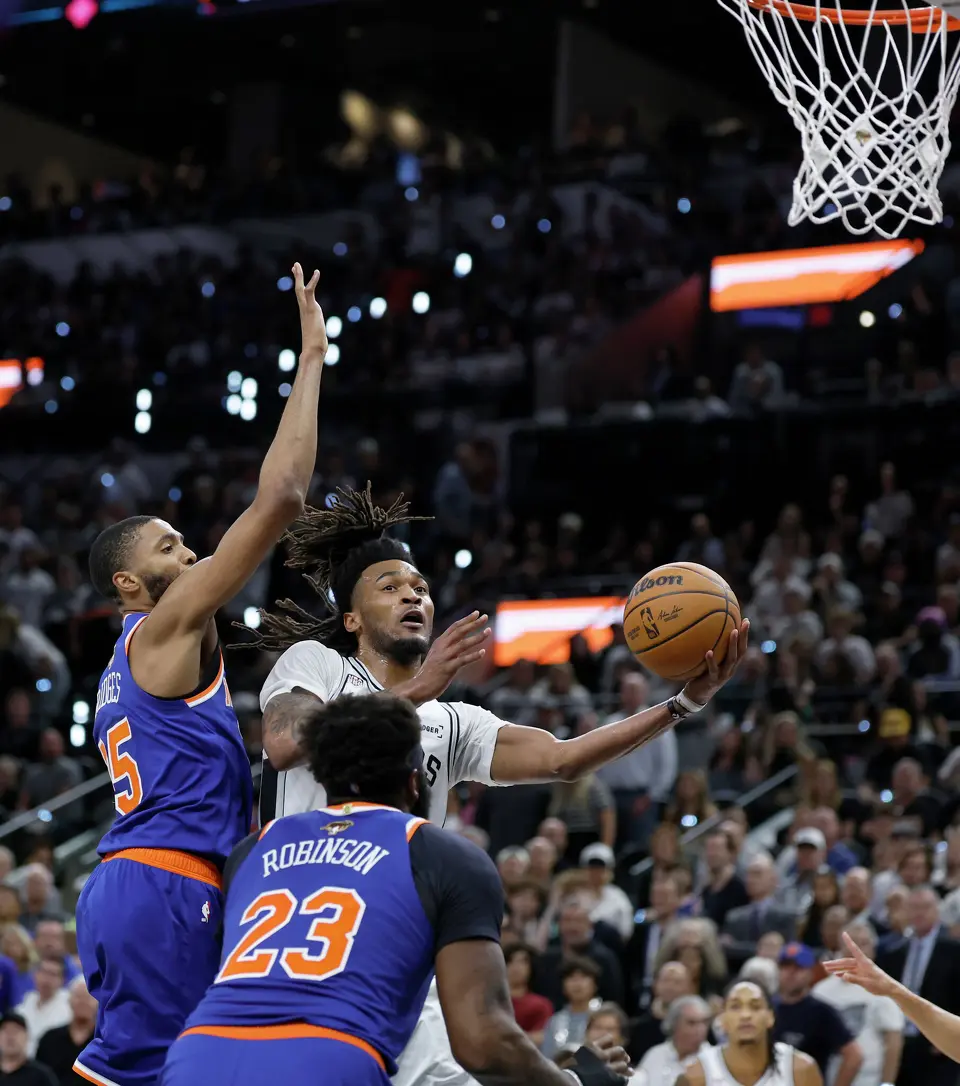 San Antonio Spurs guard Stephon Castle (5) works his way past New York Knicks guard Mikal Bridges (25) and New York Knicks center Mitchell Robinson (23) during the third quarter of Game 2 of the NBA Championship at Frost Bank Center in San Antonio on Friday, June 5, 2026.