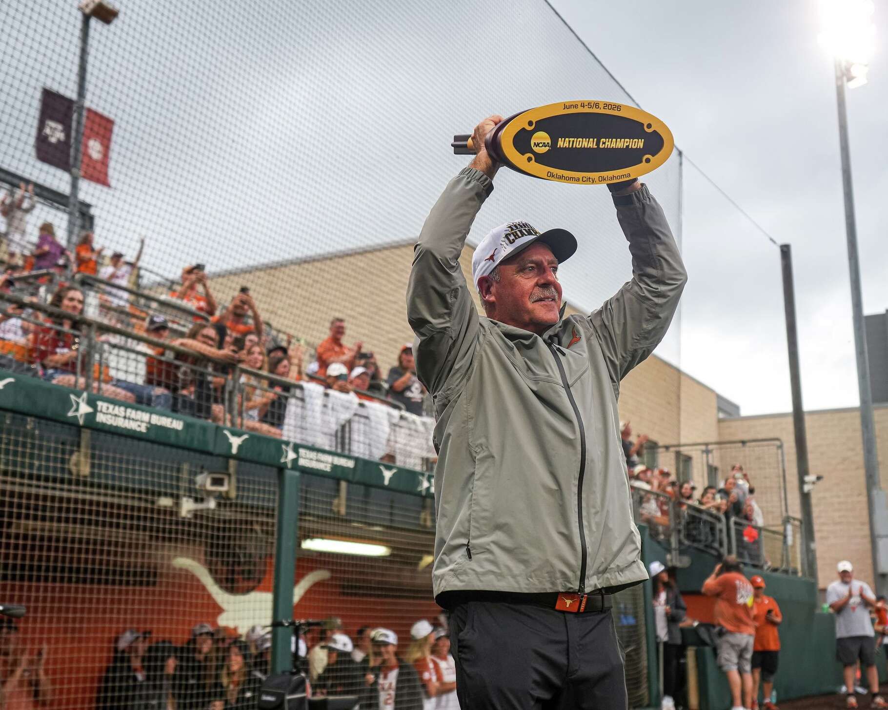 Texas Longhorns head coach Mike White holds up the 2026 national championship trophy as he takes the field at a national championship celebration at Red & Charline McCombs Field on Friday, June 6, 2026 in Austin.