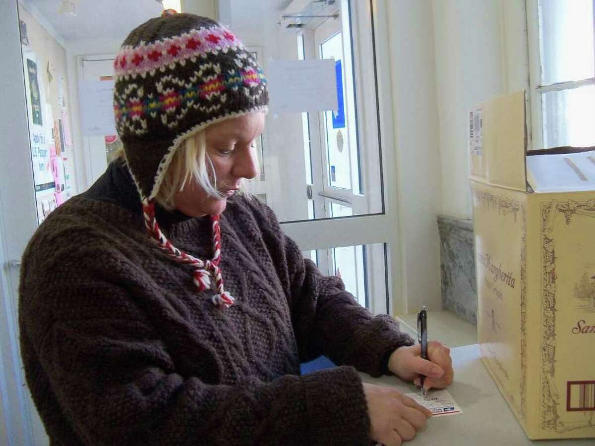 Westport resident Melanie Smith fills out a mailing label in the lobby of the U.S. Post Office on Post Road East Tuesday morning. She's hoping the Christmas gift she bought for her aunt in Tennessee gets there on time.