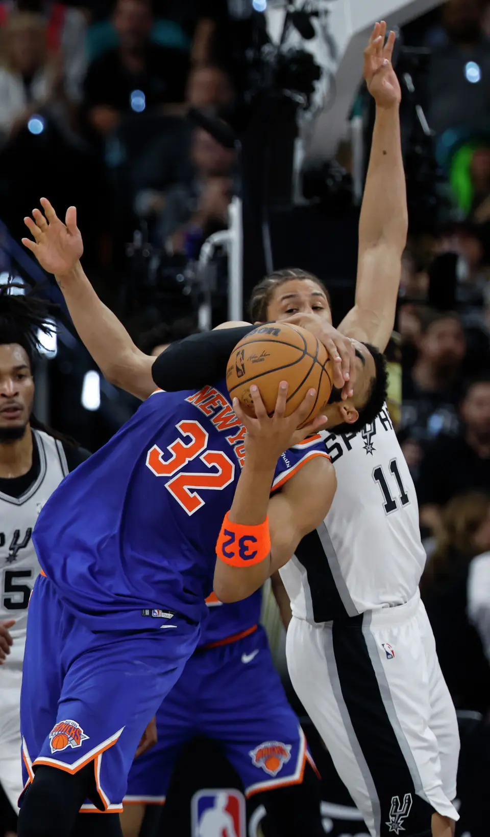 New York Knicks center Karl-Anthony Towns (32) takes a shot to the face from San Antonio Spurs forward Carter Bryant (11) during the second quarter of game five of the NBA Championship at Frost Bank Center on Saturday, June13, 2026.
