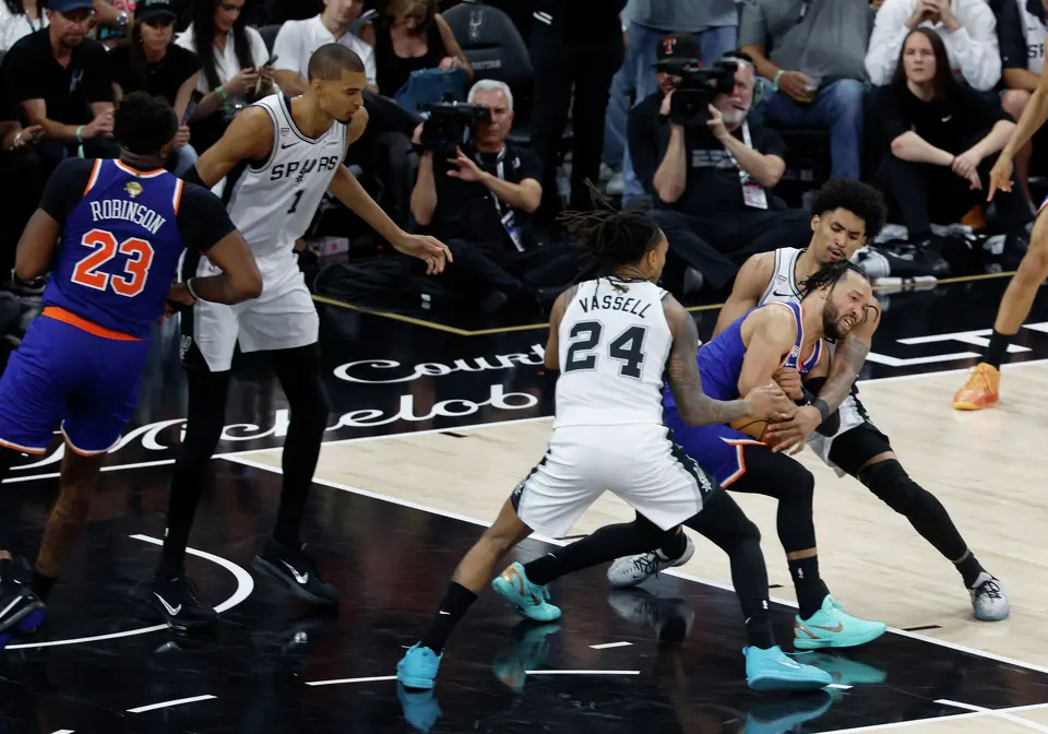 San Antonio Spurs guard Devin Vassell (24) and San Antonio Spurs guard Dylan Harper (2) swarm New York Knicks guard Jalen Brunson (11) during the third quarter of game five of the NBA Championship at Frost Bank Center on Saturday, June13, 2026.