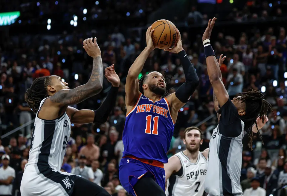 New York Knicks guard Jalen Brunson (11) takes a jump shot in between San Antonio Spurs guard Devin Vassell (24) and San Antonio Spurs guard Stephon Castle (5) during the second quarter of game five of the NBA Championship at Frost Bank Center on Saturday, June13, 2026.