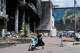 A mother pushes a stroller past a damaged building covered with street artist paintings and a big city marketplace that was destroyed recently by Russian missiles in Kyiv, Ukraine, Monday, June 22, 2026.