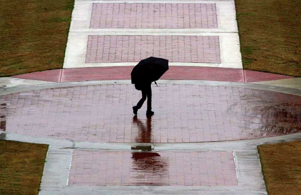 A pedestrian walks through the rainy conditions at the University of Texas at San Antonio downtown campus Thursday February 11, 2010. Cold and wet conditions persisted throughout the day. JOHN DAVENPORT/jdavenport@express-news.net