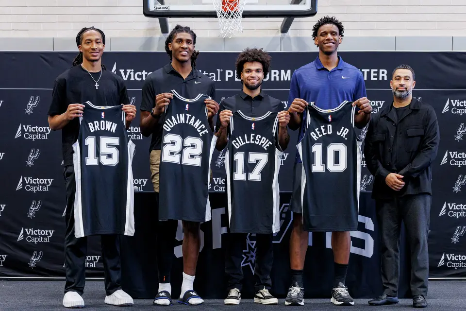 Spurs rookies Maliq Brown, from left, Jayden Quaintance, Ja’Kobi Gillespie and Tarris Reed Jr. hold up their jerseys as they pose with Spurs general manager Brian Wright during an introductory news conference at Victory Capital Performance Center, Thursday, June 25, 2026, in San Antonio.