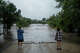 Mike Erulenfeld and Kala Martin watch as the Pedernales River floods near Old Kerr Highway on Thursday, July 16, 2026, in Fredericksburg, Texas. (AP Photo/Joel Angel Juarez)