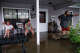 Bill Dozier, left, and Sharon Dozier sit on their flooded front porch as they talk with their grandson, Skylor Dozier, who lives in a trailer on their property along North Camp Street in Uvalde on Thursday, July 16, 2026. The Doziers said water was ankle-deep inside their house Thursday morning.