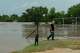 Mark Isbell, owner of Arrowhead Creek Vineyards, opens a gate alongside his dog, Perdenales, as the Perdenales River floods his property in Stonewall, Thursday, July 16, 2026. Isbell, his wife Kim and their dog were able to evacuate the RV they reside in on the property before the flood swelled and overtook their home.