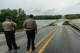 Gillespie County Sheriff's Officers stand watch as people gather to watch the Perdenales River flood Ranch Road 1623 in Stonewall, Thursday, July 16, 2026.
