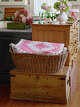 Here, a pink-and-white quilt from Weston Table is placed in a wicker basket, adding a cozy touch.