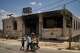 Children stand outside a mosque that was burned during an attack by Israeli settlers early in the morning in the West Bank village of Qusra, Sunday, July 26, 2026, as on its wall a Hebrew graffiti reads "Revenge Benayahu", referring to an Israeli settler killed during clashes with Palestinians in the village of Tell, last Friday.