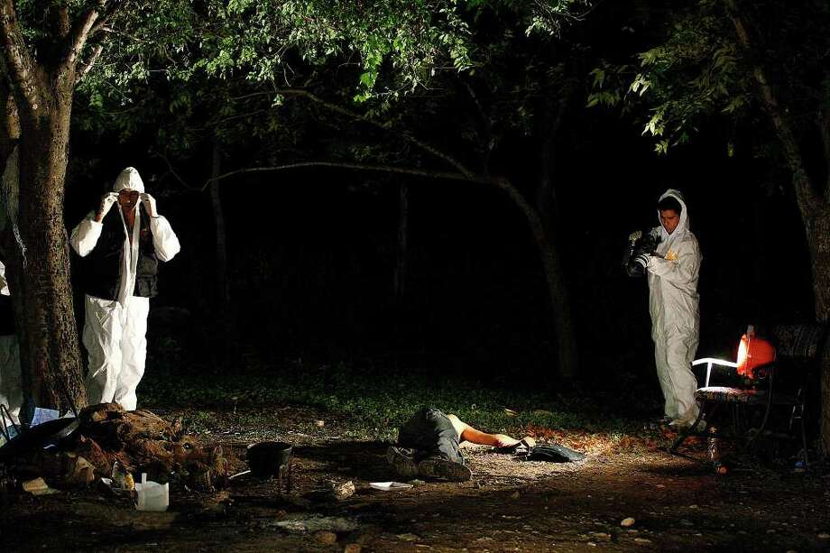 Members of a Nuevo Leon forensic unit document the scene of a confrontation between the Mexican army and alleged kidnappers at a ranch just west of Ceralvo, Mexico, on Sept. 29, 2010. The army responded to a call of men holding kidnap victims at the ranch, and a gunfight broke out when they arrived. Four of the kidnappers were killed, and four of the victims were rescued. According to Gen. Cuauhtemoc Antunes, the victims were laborers from the Ceralvo area. Photo: Jerry Lara, Staff Photographer / glara@express-news.net