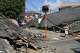 A person walks past the houses collapsed in an earthquake in Yatsushiro, Kumamoto Prefecture, southern Japan, Friday, July 31, 2026. (Koji Harada/Kyodo News via AP)
