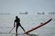 A man paddles a stand-up paddleboard as cargo ships and other commercial vessels appear anchored in the Strait of Hormuz off Bandar Abbas, Iran, Monday, July 27, 2026. (Razieh Poudat/ISNA via AP)