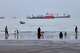 People spend time at a beach as commercial vessels are anchored in the Strait of Hormuz off Bandar Abbas, Iran, Wednesday, Aug. 5, 2026. (Amirhosein Khorgooi/ISNA via AP)