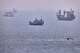 A small boat sails past cargo ships and other commercial vessels anchored in the Strait of Hormuz off Bandar Abbas, Iran, Wednesday, Aug. 5, 2026. (Amirhosein Khorgooi/ISNA via AP)