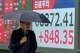 A person walks in front of an electronic stock chart board showing Japan's Nikkei index at a securities firm Thursday, Aug. 13, 2026, in Tokyo.