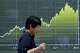 A person walk in front of an electronic stock chart board showing Japan's Nikkei index at a securities firm Thursday, Aug. 13, 2026, in Tokyo.