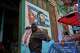 A man carries a pig at the entrance of a market, decorated with a mural of Fidel Castro, in Havana, Cuba, Wednesday, Aug. 12, 2026.