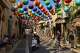 People walk beneath an art installation of colorful spheres along a pedestrian street in Jaffa, a mixed Jewish-Arab neighborhood of Tel Aviv, Israel, Sunday, Aug. 16, 2026.
