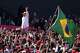 Brazilian President Luiz Inacio Lula da Silva waves to supporters as a Brazilian flag is held nearby during a presidential election campaign rally in Sao Bernardo do Campo, Sao Paulo state, Brazil, Sunday, Aug. 16, 2026.