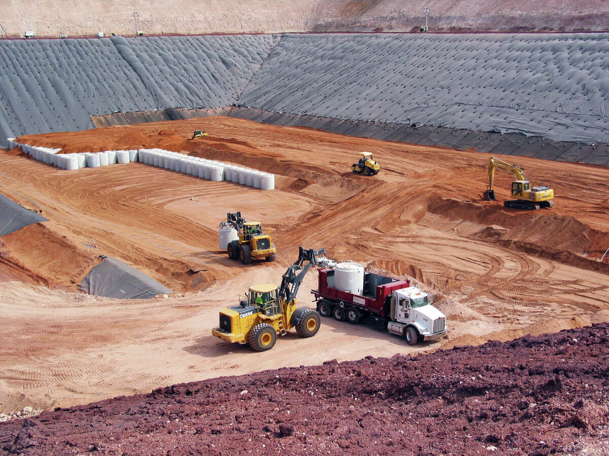 Canisters filled with uranium byproduct waste are placed into a burial pit at the Waste Control Specialists site near Andrews.