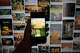 A hand holds a phone displaying screenshots from the animated Chinese film “Niu Lai” in front of a collection of fan remixes. The low-budget movie became a viral box office phenomenon after its extremely low production quality drew attention from cinemagoers.