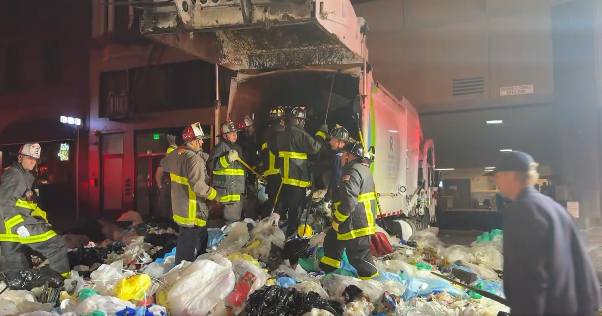 S.F. first responders work to rescue person trapped inside a Recology garbage truck