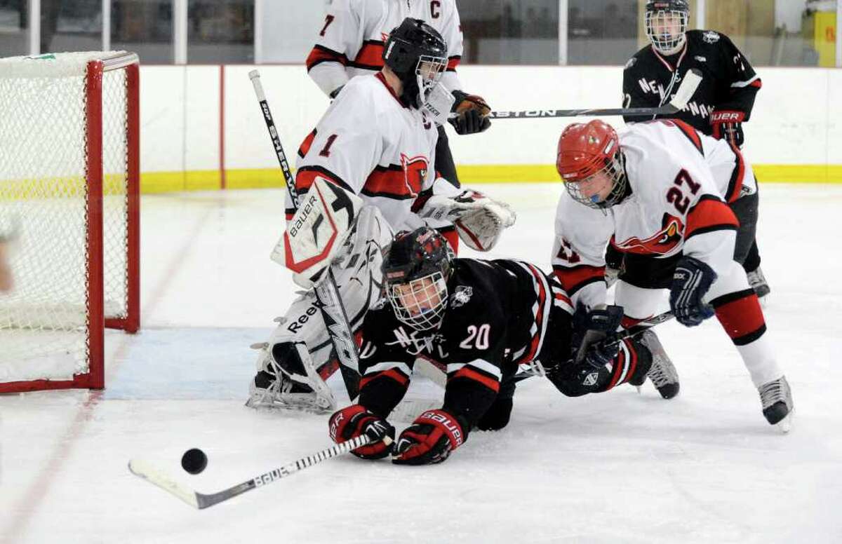 PT Prins of New Canaan High School, # 20, center, gets checked to the ice by Craig Macken, # 27 of Greenwich High School, right, as GHS goalie Ricky Piper, left, looks for the puck during second period action of hockey game between Greenwich High School vs. New Canaan High School at Hamill Rink, Byram, Thursday night, Dec. 23, 2010.