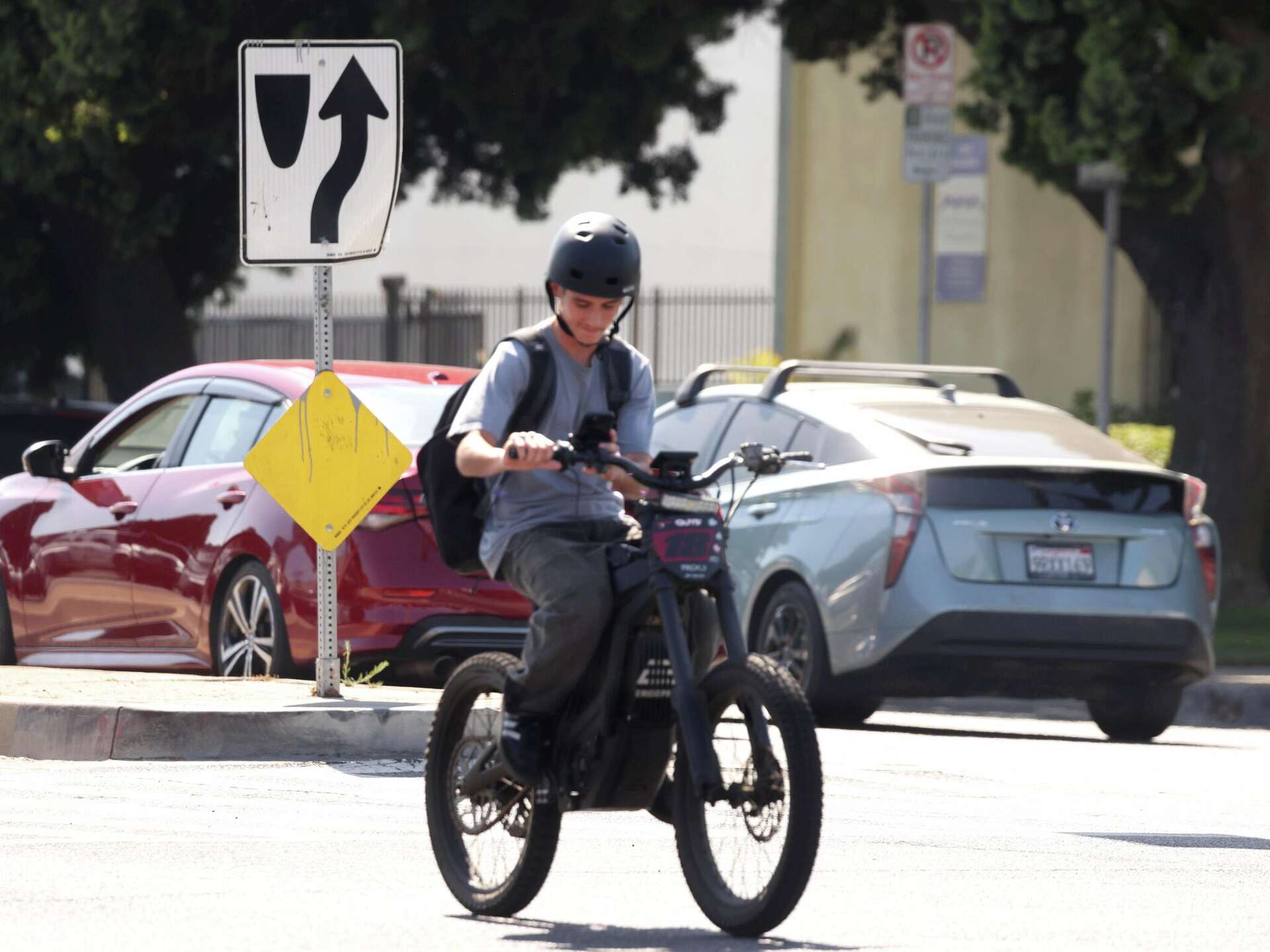 A young person looks at his smart phone while riding in the fast lane down Venice Boulevard in Los Angeles on Aug. 21, 2026.