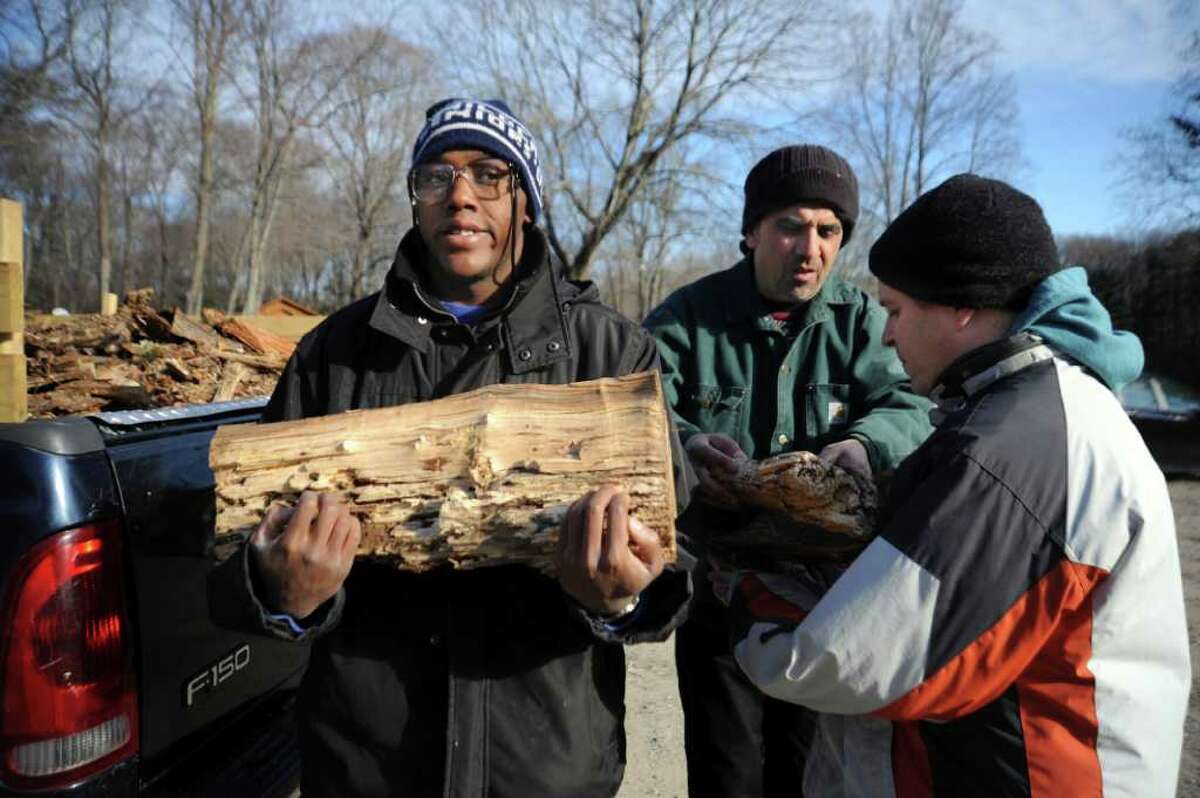 John Kelly, of Abilis, center, helps clients Theo Brown, left and Scott Gortz, right with some of the wood they have chopped, at Camp Seton, on Monday, Dec. 20, 2010. Abilis is expanding its firewood sales, with help from the Boy Scouts.