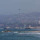 FILE - Surfers take a lesson at Venice Beach while a Los Angeles Police Department (LAPD) helicopter flies over the beach with the Santa Monica Pier in the background, on Aug. 6, 2026.